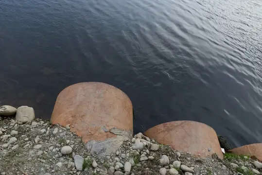 Два больших камня на каменистом берегу у тёмной воды