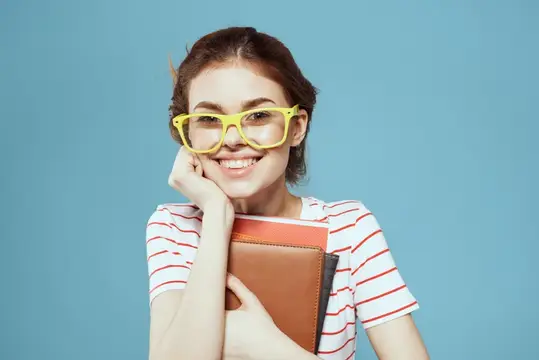 Улыбчивая девушка в жёлтых очках с блокнотом на голубом фоне