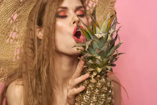 Девушка с ярким макияжем и ананасом на розовом фоне