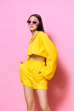 Азиатская девушка в жёлтом костюме и розовых очках на розовом фоне