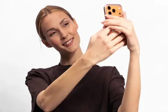 Молодая блондинка делает селфи на смартфон на белом фоне
