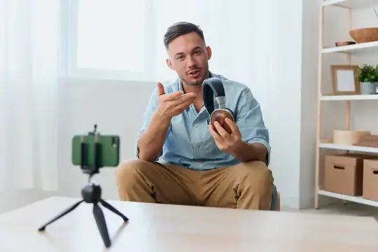 Молодой мужчина записывает видео с наушниками на смартфоне
