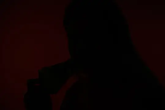 Силуэт девушки с длинными волосами на тёмно-красном фоне