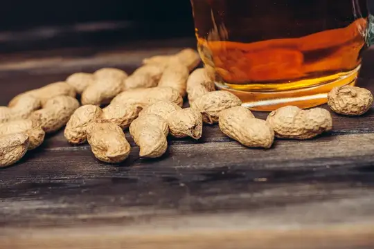Земляные орехи и стакан янтарного напитка на деревянном столе