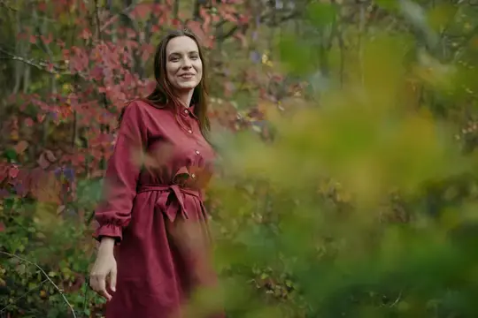 Мягкие, землистые тона окружают ее, легкий ветерок шевелит листья, создавая спокойное настроение и искреннюю связь с природой в естественном, жизненном моменте