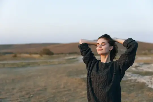 Молодая женщина с закрытыми глазами отдыхает на природе в сумерках