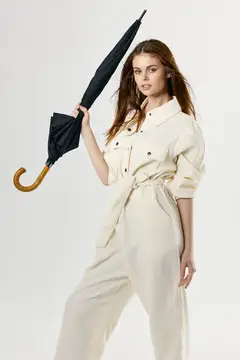 Женщина в модной одежде держит в руках зонт, защищаясь от дождя