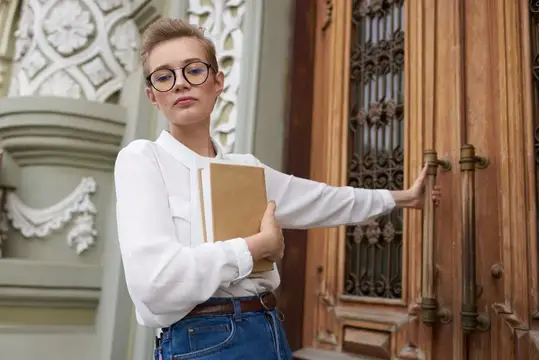 Студент с книгой в руках на открытом воздухе, читает
