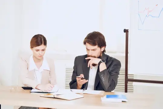 Мужчина и женщина сосредоточенно работают с документами в офисе