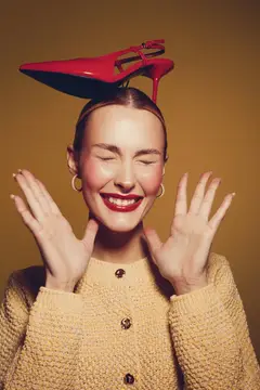 Улыбающаяся девушка с красной туфлей на голове