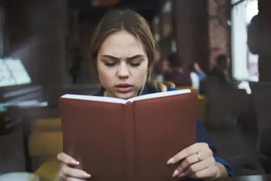 Деловая женщина с книгой в руках и чашкой кофе в кафе, ведущая активный образ жизни