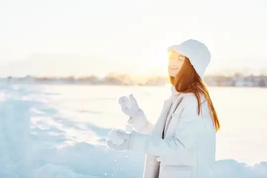 Красивая женщина в зимней одежде гуляет по снегу, наслаждаясь холодом и отдыхом на природе