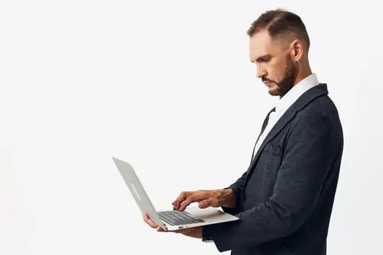 Бородатый мужчина в тёмном пиджаке работает за ноутбуком