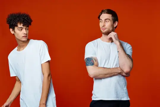 Двое парней в белых футболках на красном фоне