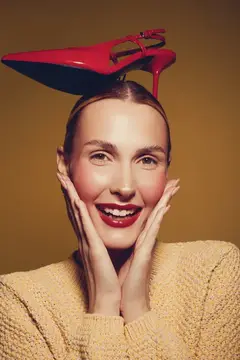 Улыбающаяся девушка с красной туфлей на голове