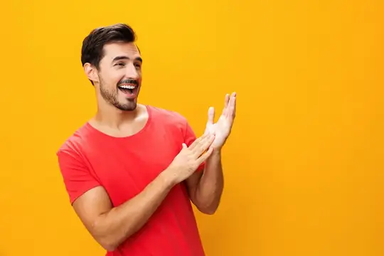 Улыбающийся бородатый мужчина в красной футболке хлопает в ладоши на жёлтом фоне