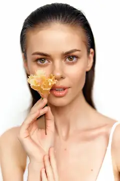 Молодая женщина с цветком у лица на белом фоне