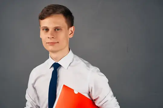 Молодой человек в белой рубашке с красной папкой на сером фоне