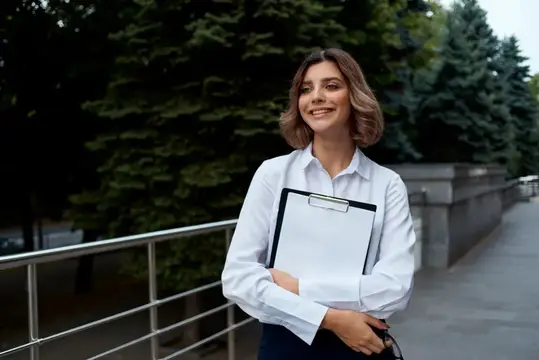 Улыбающаяся женщина с планшетом в руках на улице