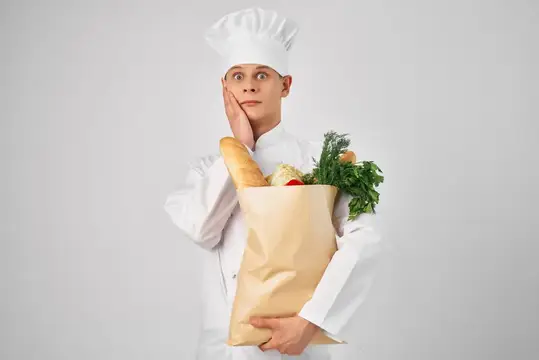 Задумчивый повар в колпаке с бумажным пакетом продуктов