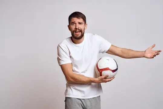Мужчина с футбольным мячом играет, тренируется на светлом фоне