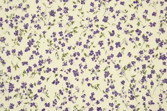 Элегантный цветочный узор из множества мелких фиолетовых цветов, рассыпанных на мягком кремовом фоне