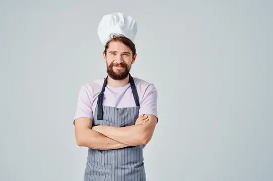 Мужчина в поварской форме готовит на кухне ресторана среди профессионалов