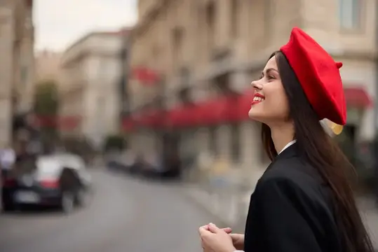 Модная женщина улыбается с зубами, стоя на улице на фоне города