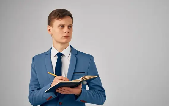 Молодой человек в синем костюме с блокнотом и карандашом