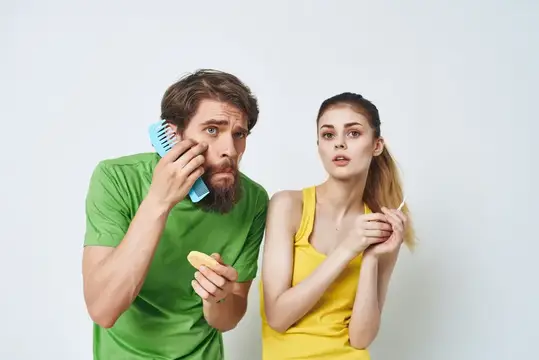 Бородатый мужчина с расчёской и девушка в жёлтой майке на белом фоне