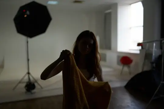 Девушка с желтым пледом в темной фотостудии