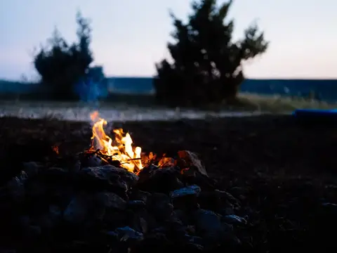 Яркий костёр горит среди камней на фоне сумеречного поля