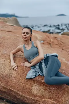 Молодая женщина в спортивной одежде отдыхает на скалах у моря