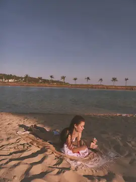 Женщина отдыхает на песчаном пляже у воды, на заднем плане видны пальмы