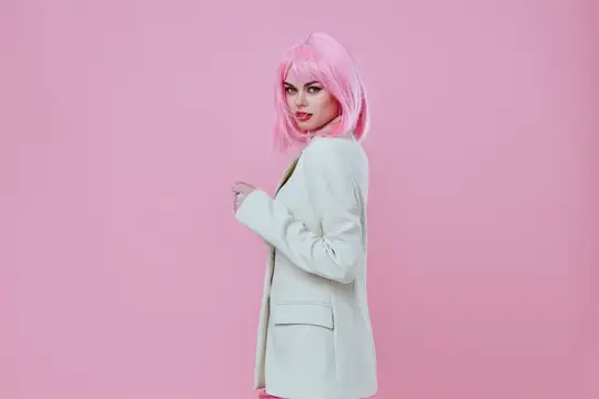 Красивая модная женщина в современном стиле с розовыми волосами и красными губами позирует на розовом фоне
