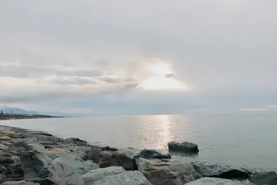 Спокойное море с каменистым берегом под облачным небом
