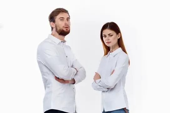 Женщина и мужчина в белых рубашках стоят рядом друг с другом, скрестив руки на груди