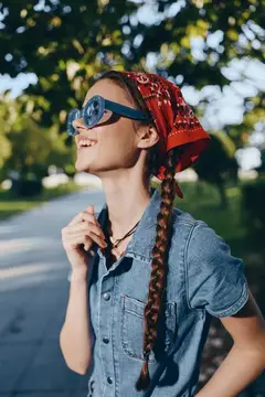 Улыбающаяся девушка в красной бандане и солнцезащитных очках на улице