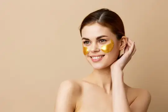 Улыбающаяся молодая женщина с золотыми патчами под глазами