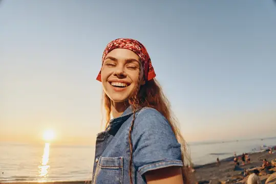 Улыбающаяся девушка в красной бандане на закатном пляже у моря