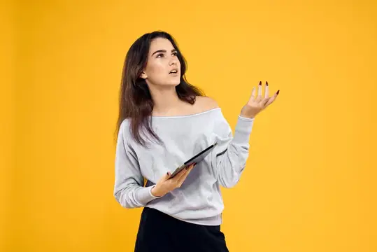 Брюнетка со смартфоном жестикулирует на жёлтом фоне