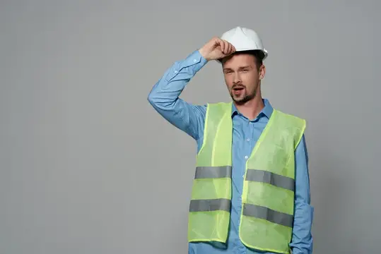 Удивлённый мужчина в каске и светоотражающем жилете