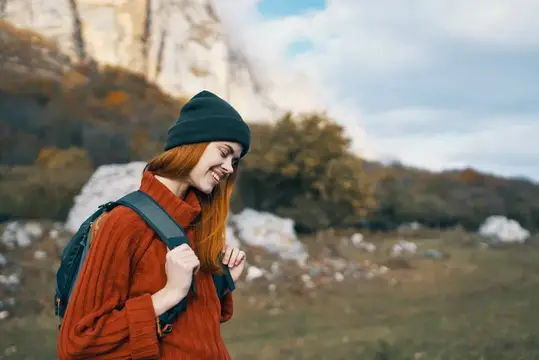 Жизнерадостная женщина-туристка с рюкзаком идет пешком, отдых, свобода, горы