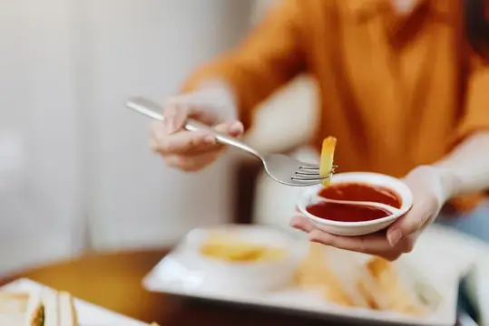 Крупный план человека, макающего хрустящий картофель фри в кетчуп