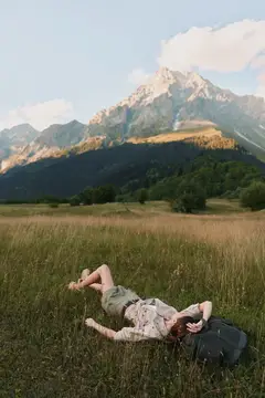 Девушка лежит на траве на фоне горного пейзажа