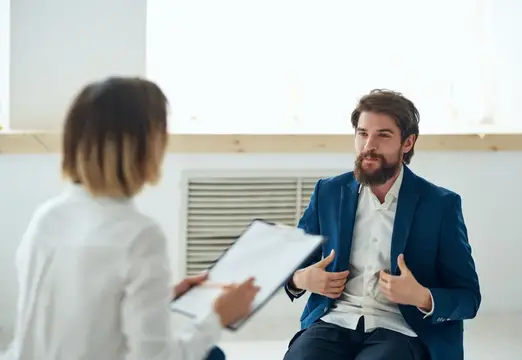 Бородатый мужчина в синем пиджаке на приёме у врача