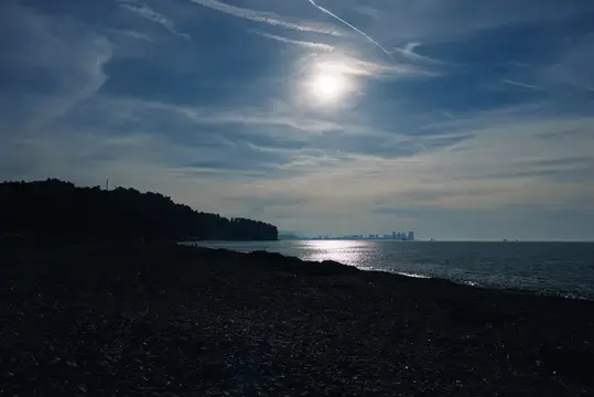 Солнце над морем и тёмный берег в вечерних сумерках