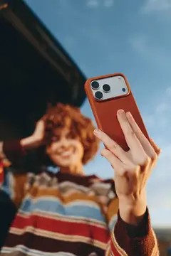 Рыжеволосая девушка с телефоном в руке на фоне неба