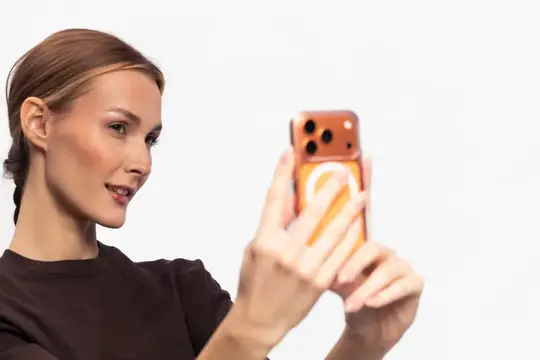 Молодая женщина делает селфи на смартфон в оранжевом чехле