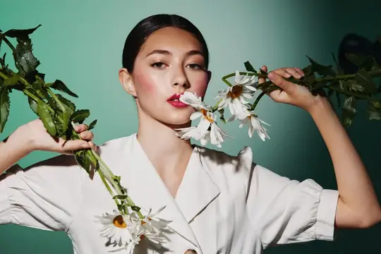 Молодая женщина с белыми ромашками на бирюзовом фоне